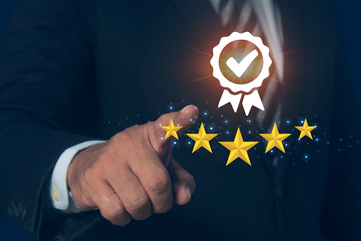 Businessman pointing the best quality assurance with golden five stars for guarantee product. Industry-leading digital technology product performance concept and ISO certification.
