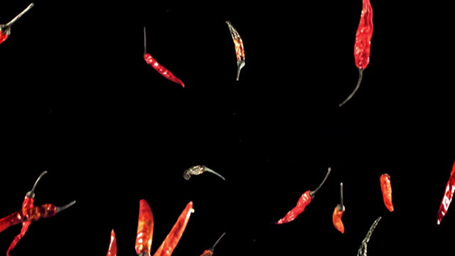 Super slow motion dried chili peppers fly up and fall down