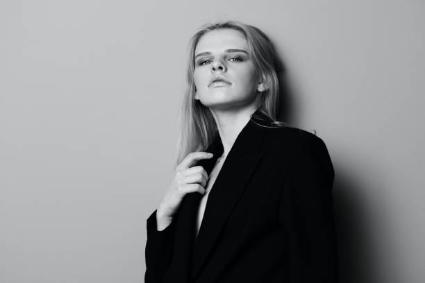 istock Gorgeous young stylish lady in jacket posing leaning on the wall at studio. Pretty female blonde model sexy looking at camera 2147687464