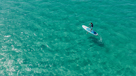 Drone shots of paddle boarder riding a SUP on the sea