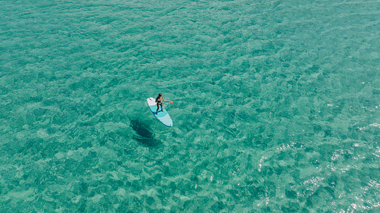 Drone shots of paddle boarder riding a SUP on the sea