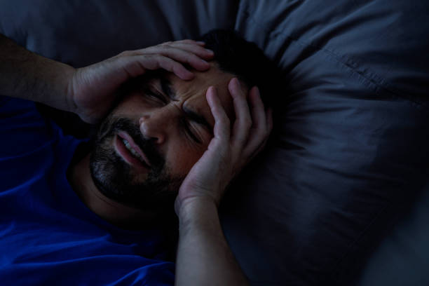 istock Bearded young man waking up with a headache, touching his head, having a migraine or having a hangover, copy space 2147688695