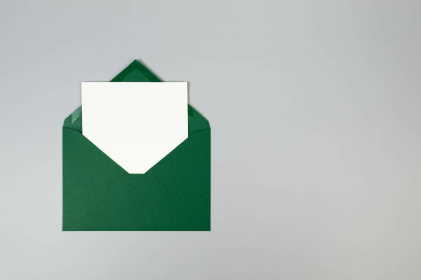 istock Top view of green envelope, white card on grey background. 2147688798
