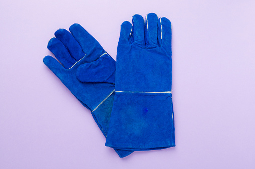 Blue construction gloves on color background, top view