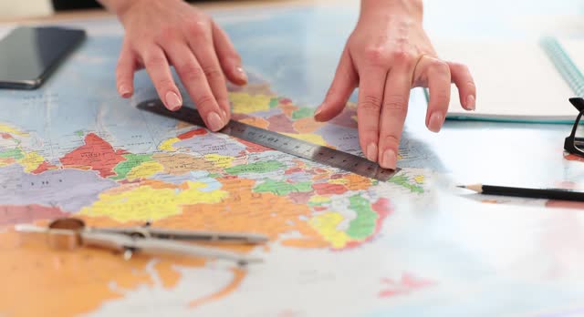 Woman makes markings with ruler while guiding flat map
