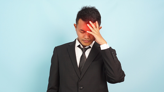 Man wearing black suit migraine and headache stand on blue background