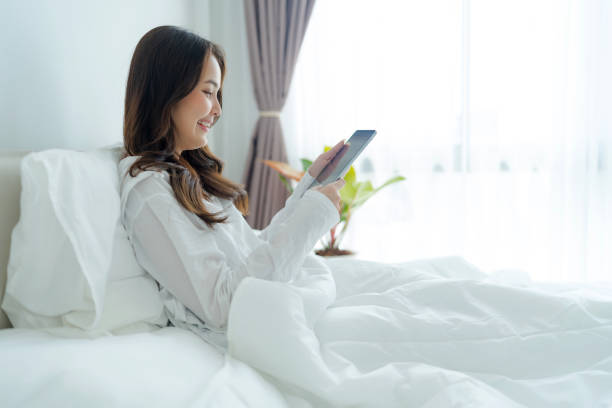 istock Girl lying in bed playing tablet computer in bedroom 2147689495