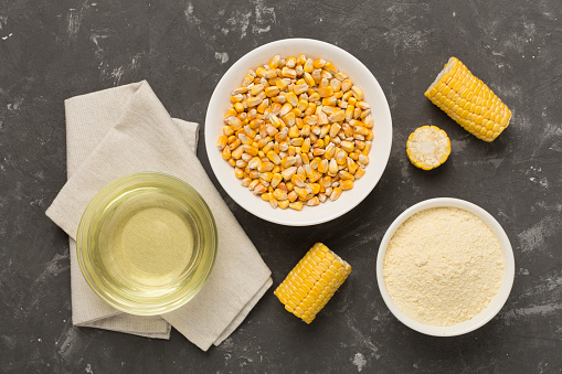 Maize products with fresh corn cobs on concrete background, top view