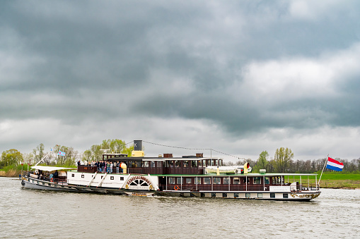 Paddle saloon boat Kapitein Anna side paddle-wheeler ship on the river IJssel near Kampen during the 2024 Sail Kampen event. A paddle steamer is a steamship or steamboat powered by a steam engine that drives paddle wheels to propel the ship through the water.
