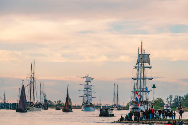 Ships sailing on the river IJssel in Kampen during the 2024 Sail Kampen event. People are watching the boats sailing by from the shore.