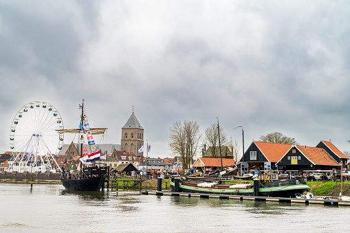 Historic replica sailing boat Kamper Kogge at the Kogge ship yard on the river IJssel during the 2024 Sail Kampen event in the Hanseatic league city of Kampen in Overijssel, The Netherlands. People on board are looking at the view and a crowd on the quay is watching the ships.