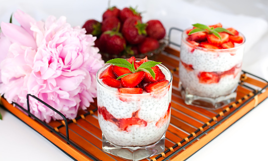 A healthy breakfast dessert with strawberries, yogurt and chia seeds on a wicker tray. Delicious natural and healthy dessert. lose-up.