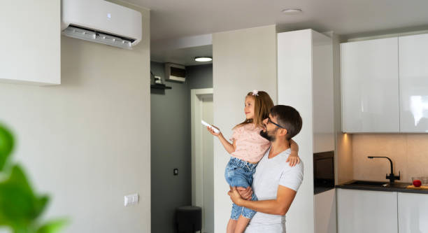 istock Father and little girl turn on air conditioner using remote control 2147693525