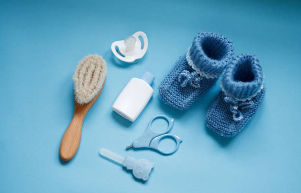 istock Baby boy accessories background, booties, tiny rod, soother, brush, over blue background 2147693589