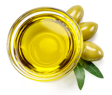 Glass bowl of olive oil and olive berries isolated on white background.  Top view.