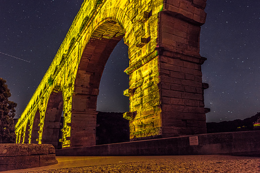 The Pont du Gard is an ancient Roman aqueduct, that is depicted  on five euro note. Bridge lit up at night time. Summer 2022.