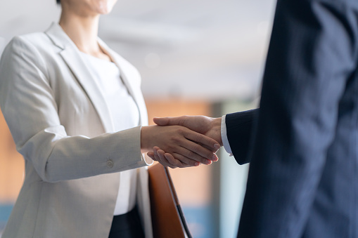 Close up shot of an Asian businesswoman and businessman shaking hands after closing a business deal