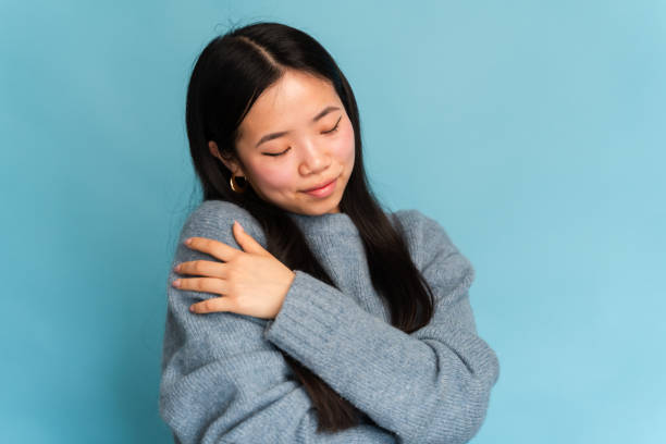 istock Serene young woman embracing herself on blue backdrop 2147695928