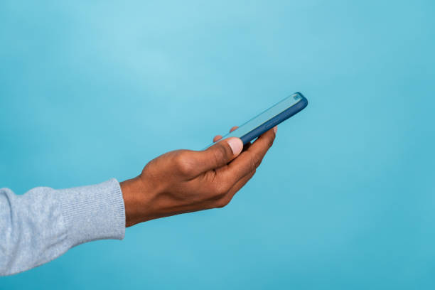 istock Hand holding smartphone against blue background 2147695995