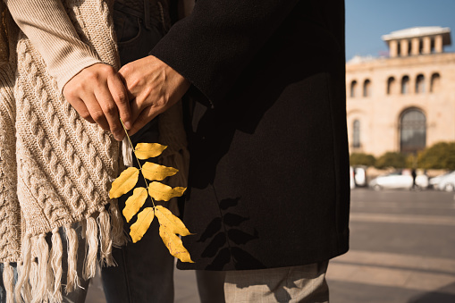 Autumn in Armenia. Hands of couple in love holding golden leaf at Republic square in Yerevan. Unrecognizable people