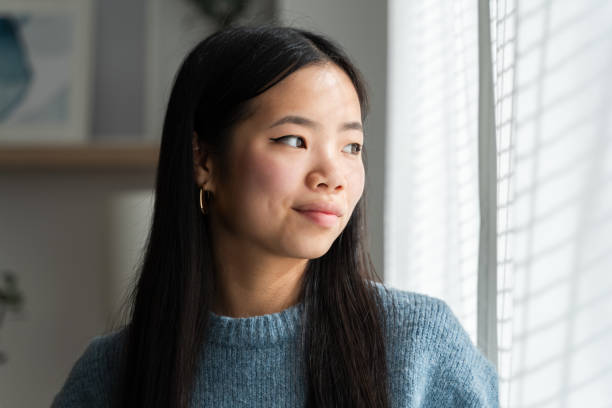 istock Young woman gazing through window 2147696778