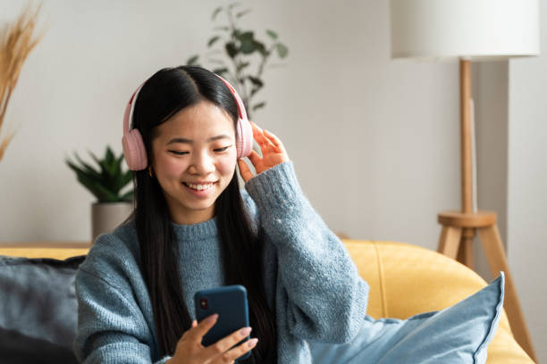 istock Young woman enjoying music on smartphone at home 2147696830