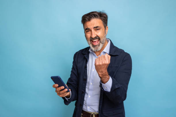 istock Successful businessman celebrating with smartphone 2147697179