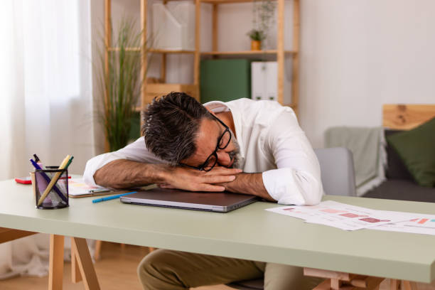 istock Exhausted businessman asleep at desk 2147697579