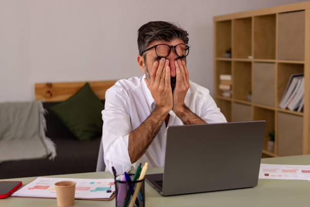 istock Frustrated man at work covering face with hands 2147697613