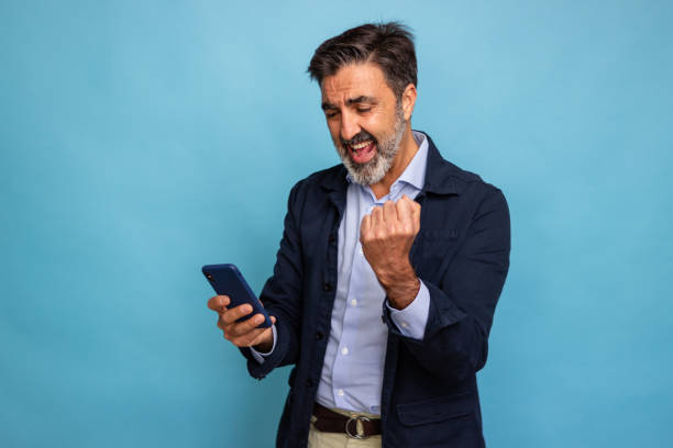 istock Excited businessman celebrating success with smartphone 2147698041