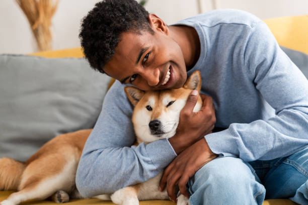 Happy man embracing pet shiba inu on sofa