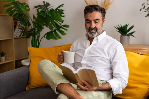 istock Relaxed man enjoying book and coffee at home 2147698095