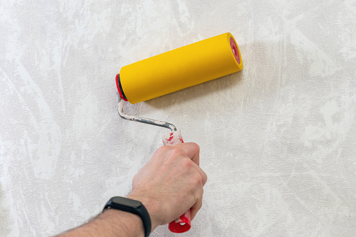 A man's hand with a roller for smoothing wallpaper. Wallpapering the apartment.