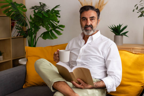 istock Man enjoying book and coffee on sofa 2147698936