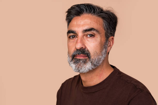 Mature man with grey beard on beige background