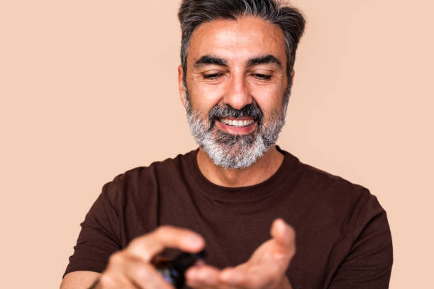 istock Smiling mature man applying moisturizer on hands 2147698956