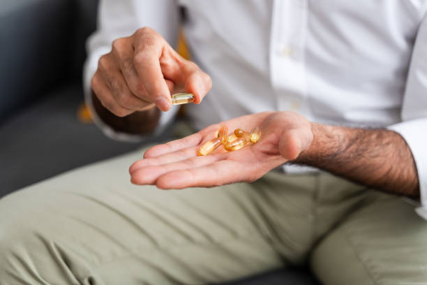 istock Man holding omega-3 fish oil capsules 2147700184