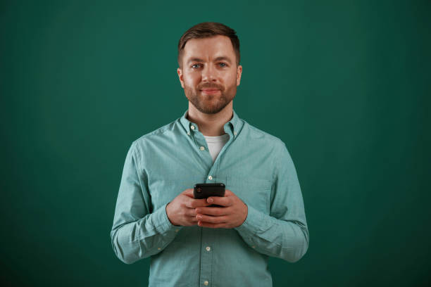 istock Black smartphone in hands. Man is standing against background in the studio 2147701403