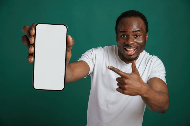 istock Smartphone with white empty space for text. African American man is standing against green background in the studio 2147701476