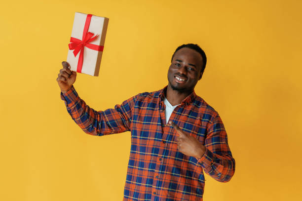 istock Holidays gift box in hand. Black man is in the studio against yellow background 2147703303