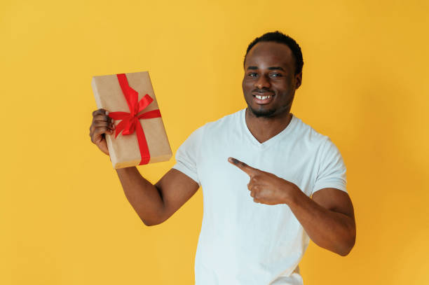 istock Holidays gift box in hand. Black man is in the studio against yellow background 2147703319