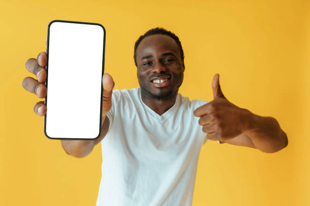 istock White display of smartphone for copy space. Black man is in the studio against yellow background 2147703388