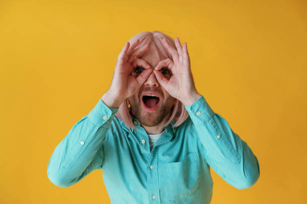 istock Making facial expression, hand gestures. Guy with pink hair is posing against yellow background 2147703499