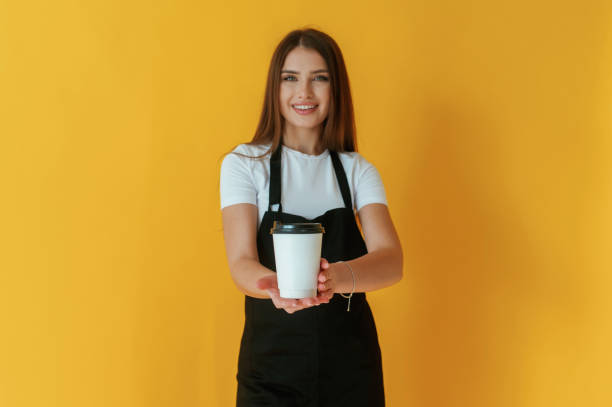 istock Nice coffee cup. Young woman is against yellow background 2147704402