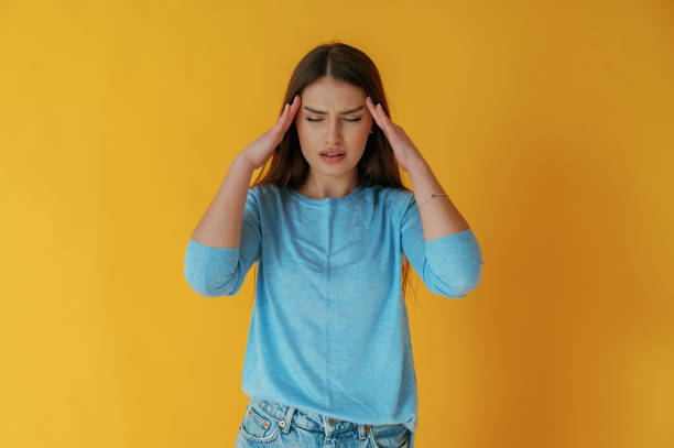 istock Bad headache. Young woman is against yellow background 2147704530