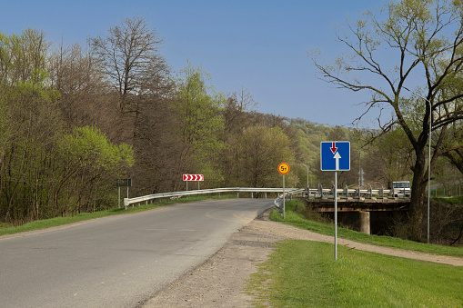 Priority road signs in road before bridge across the river in Europe