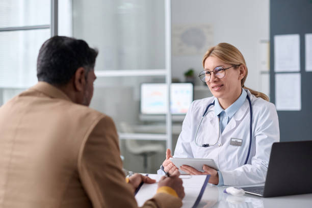 istock Smiling Female Doctor Talking to Middle Eastern Man 2147705579