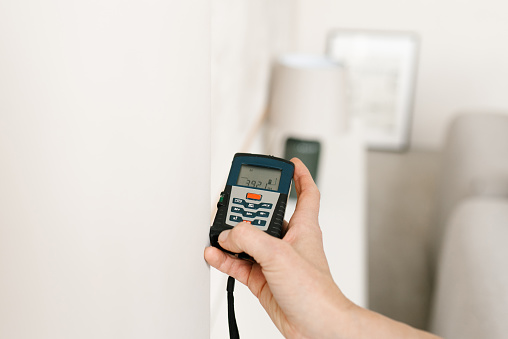 Laser rangefinder in the hands of a woman. An engineer holding a laser rangefinder. Close up of a measuring device in a house. Designer using an electronic rangefinder in a room