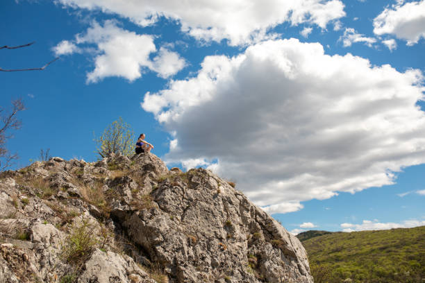 A young woman admiring nature on a mountain peak while on a hiking trip