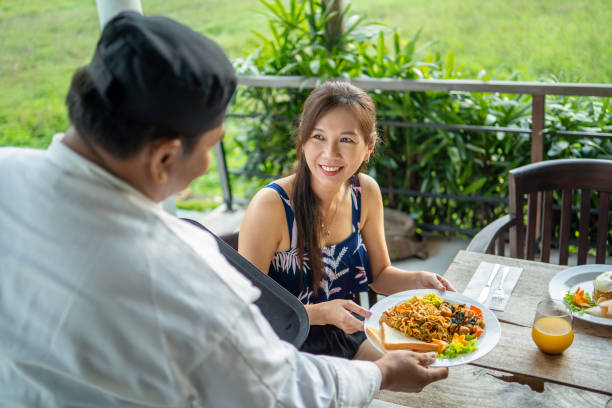 istock Friendly waiter serving food to guests at restaurant 2147706478